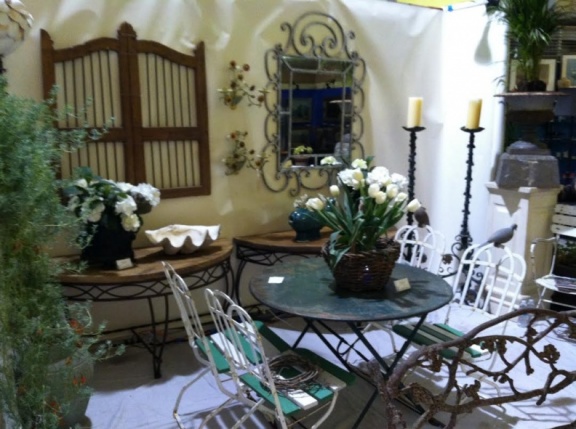 Garden design elements including tall iron candle sticks, round metal table, wood and metal chairs.