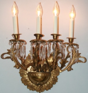 One of a pair of antique four arm well detailed brass wall sconces with dangling crystals.