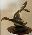 Beautifully graceful metal swan sculpture mounted on black marble. Measures approximately 28" high x 26 1/2" wide. 